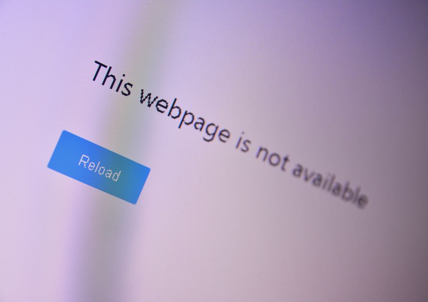 A computer screen displays an error message reading “This webpage is not available” with a reload button below it.