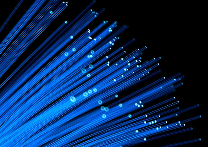 lose-up abstract view of glowing blue fibre optic cables against a black background. Visual represents high-speed internet, data transfer, and modern fibre connectivity.