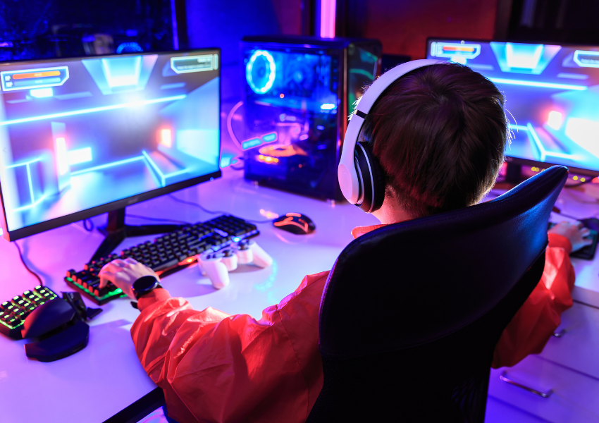 High-speed Internet gaming setup with a gamer using multiple monitors and RGB lighting for smooth, low-latency online gameplay.