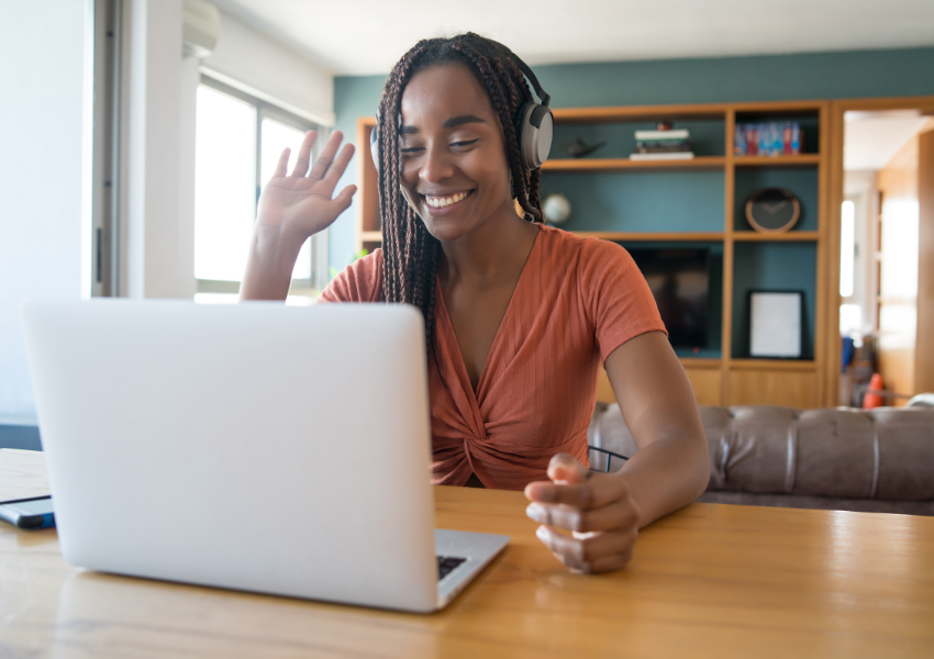Woman using Wi-Fi working remotely from a home office on a laptop during a video call.