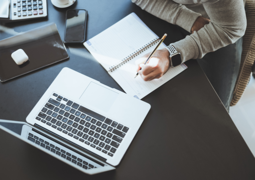 A person works from home using a combination of tech and workbooks