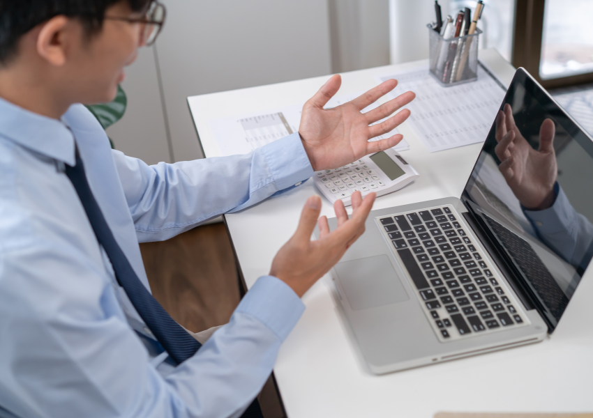 A man sits at his desk on a remote work meeting